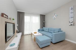 uma sala de estar com um sofá azul e uma televisão em Perfect Holiday Apartments Bel Mare by Renters em Międzyzdroje