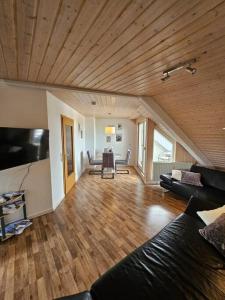 バート・ヴァルトゼーにある2 Zimmer Wohnung in Bad Waldseeの木製天井のリビングルーム(黒いソファ付)