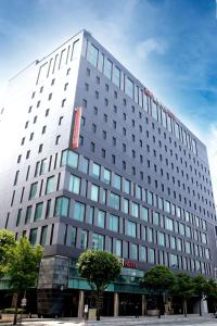 a tall white building with a red sign on it at Ibis Ambassador Suwon in Suwon