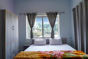 a bedroom with a bed with a large window at Sports Homestay in Lansdowne