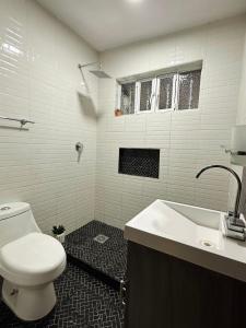 a white bathroom with a toilet and a sink at Casa Madre Santa in Aguascalientes