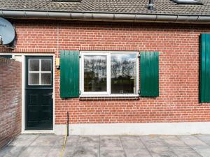 a brick building with green shutters and a window at Spacious farmhouse in Silvolde with garden in Silvolde