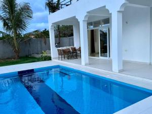 a swimming pool in front of a white house at Mich Homes in Malindi