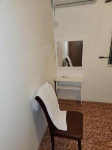 een witte stoel in een kamer met een spiegel bij Room & Scooter Rental - Mont Choisy in Grand Baie