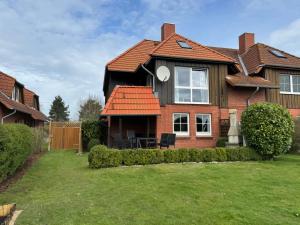 une maison avec un toit rouge et une cour dans l'établissement F4a EG - Fasanenblick, à Petersdorf auf Fehmarn