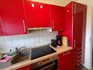 - une cuisine rouge avec un évier et des placards rouges dans l'établissement F4a EG - Fasanenblick, à Petersdorf auf Fehmarn