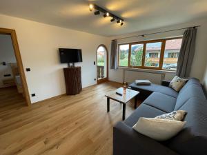 a living room with a blue couch and a tv at Ferienwohnungen Alpinum in Krün +37 photos