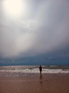 Un uomo in piedi sulla spiaggia che guarda l'oceano di Doppelzimmer 2 a Højer