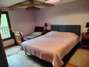 a bedroom with a bed and a chair and a window at l'Airial de Nahouns in Sabres
