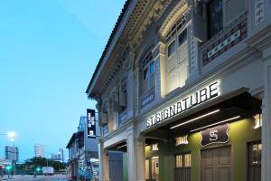 a building with a sign for a store on a street at ST Signature Jalan Besar in Singapore
