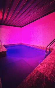 - une piscine avec des lumières roses dans une chambre dans l'établissement Sakli Cave House, à Avanos