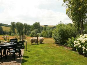 a table and chairs with sheep in a field at Lovely Farmhouse in Wijlre with Forest nearby in Wijlre