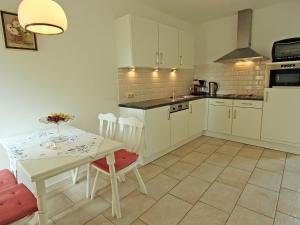 a kitchen with white cabinets and a table and chairs at Lovely Farmhouse in Wijlre with Forest nearby in Wijlre