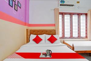 a bedroom with two beds with red pillows at SPOT ON The New View Regency in Trivandrum