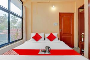 a bedroom with a bed with red pillows and a window at SPOT ON The New View Regency in Trivandrum