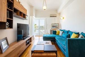 a living room with a blue couch and a tv at Athens Luxury Getaway - Pasalimani City Oasis in Piraeus