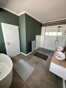 y baño con bañera, lavamanos y ducha. en The Elegant Beach House en Swakopmund