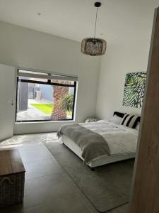 sypialnia z łóżkiem i dużym oknem w obiekcie The Elegant Beach House w mieście Swakopmund