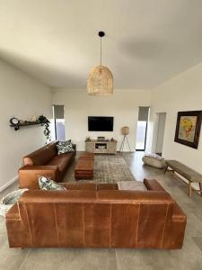 a living room with a brown couch and a flat screen tv at The Elegant Beach House in Swakopmund