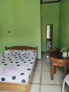 1 dormitorio con cama y mesa de madera en Xylla Guesthouse, en Siquijor