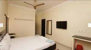 a bedroom with a bed and a tv on the wall at HOTEL BHARANI in Kanyakumari