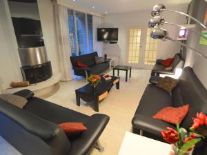 uma sala de estar com sofás pretos e uma lareira em Quaint Villa in Doornspijk with Swimming Pool em Doornspijk