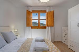 a white bedroom with a bed and a window at Villa picena las alpujarras in Picena