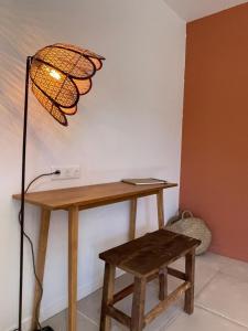 a lamp and a wooden table with a stool at Les Petites Maisons in Sotta