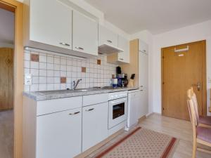 a kitchen with white cabinets and a sink at Upscale Apartment in Salzburg with terrace and country views in Hollersbach im Pinzgau