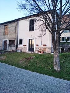 a white house with a tree in front of it at Casa Vacanze Frattura in Frattura