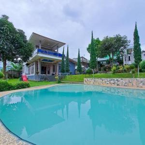 a large pool of blue water in front of a house at Villa GeGe Puncak in Cipayung
