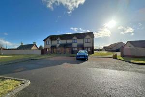 a blue car parked in front of a house at The Old Mill Apartment, on NC500 in Brora