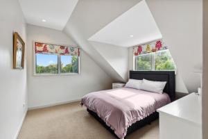 a bedroom with a bed and two windows at Relax at Redoubt - Auckland Holiday Home in Auckland