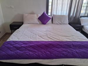 a bed with purple and white sheets and pillows at Royal homes a4 in Kushālnagar