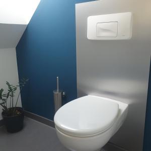 La salle de bains est pourvue de toilettes blanches et d'un mur bleu. dans l'établissement ZwischenRaum, à Wuppertal