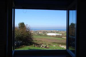 a window with a view of a field and a farm at Carmen - Habitación con vistas al mar in Santander