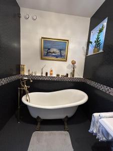 a white bath tub in a black bathroom at Rumiankowa Bis in Puck