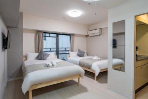 大阪市にあるLite House KuromonⅢのベッド2台とキッチンが備わるホテルルームです。