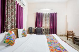 ein Schlafzimmer mit einem großen Bett mit lila Vorhängen in der Unterkunft FabExpress Corporate Stays in Ranchi