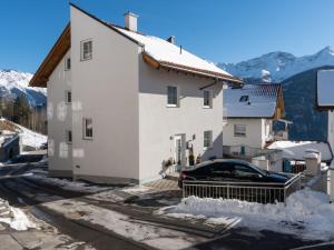 a white house with a car parked in the snow at Modern Apartment in Fiss at Ski Bus Stop in Fiss