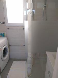 une salle de bains blanche avec un lave-linge et une fenêtre. dans l'établissement Gite Loire et Bois, à Saint-Martin-sur-Ocre