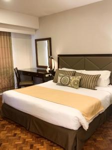 a bedroom with a large bed and a desk at The Residences Olympia in Manila