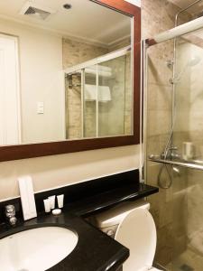 a bathroom with a toilet and a sink and a shower at The Residences Olympia in Manila