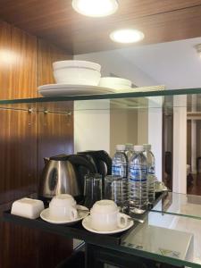 a glass shelf with dishes and bottles of water at The Residences Olympia in Manila