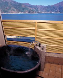 a bathroom with a bath tub and a sink at Maruei in Fujikawaguchiko