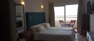sypialnia z łóżkiem, telewizorem i oknem w obiekcie Seafront apartment with open-air heated pool w mieście Fuengirola