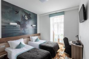 een hotelkamer met twee bedden en een tv bij Algiro Hotel in Kaunas