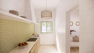 uma cozinha com paredes brancas e um balcão com uma taça de fruta em Apartamentos Punta Rasa em Cala Saona