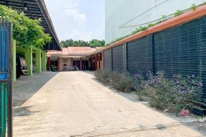an empty alley with purple flowers next to a building at Penginapan Losmen Ayu Pamanukan RedPartner in Pamanukan-hilir