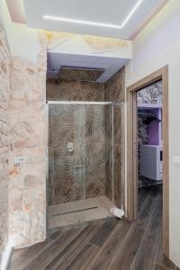 a glass shower in a room with a stone wall at LUXUITE SPA con PISCINA e JACUZZI in Alberobello